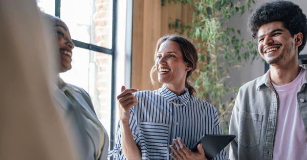 An ethnically and gender diverse team of three smiling and laughing with each other