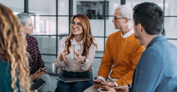 A group of employees sitting in a circle and having a coaching session in a modern office.