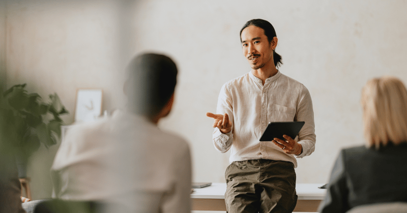 Professional man presenting with a tablet during a business meeting in a modern office. Engaged colleagues listen attentively.