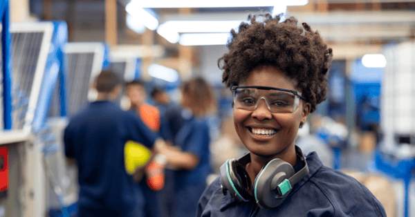 Female manufacturing employee in blue polo shirt smiling at the camera.