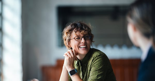 Woman in green top laughing with another woman in a meeting room