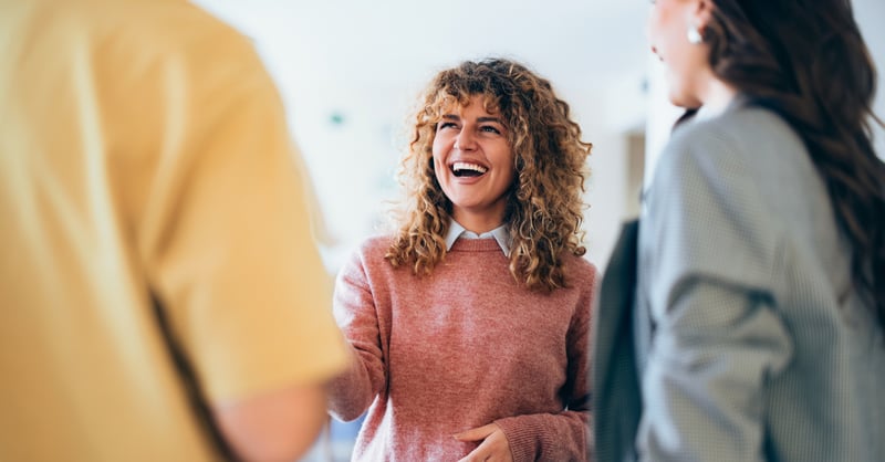 Woman in red jumper shaking hands with colleague and smiling