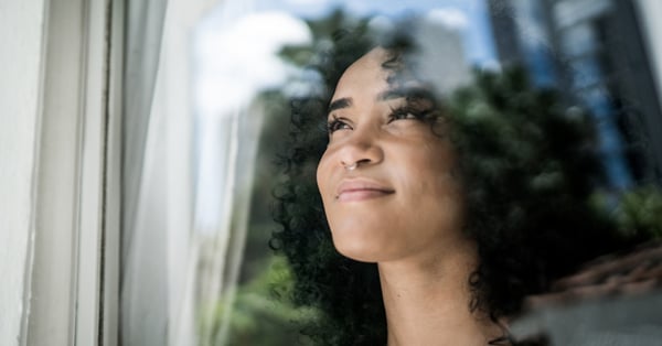 Young woman looking through window and smiling